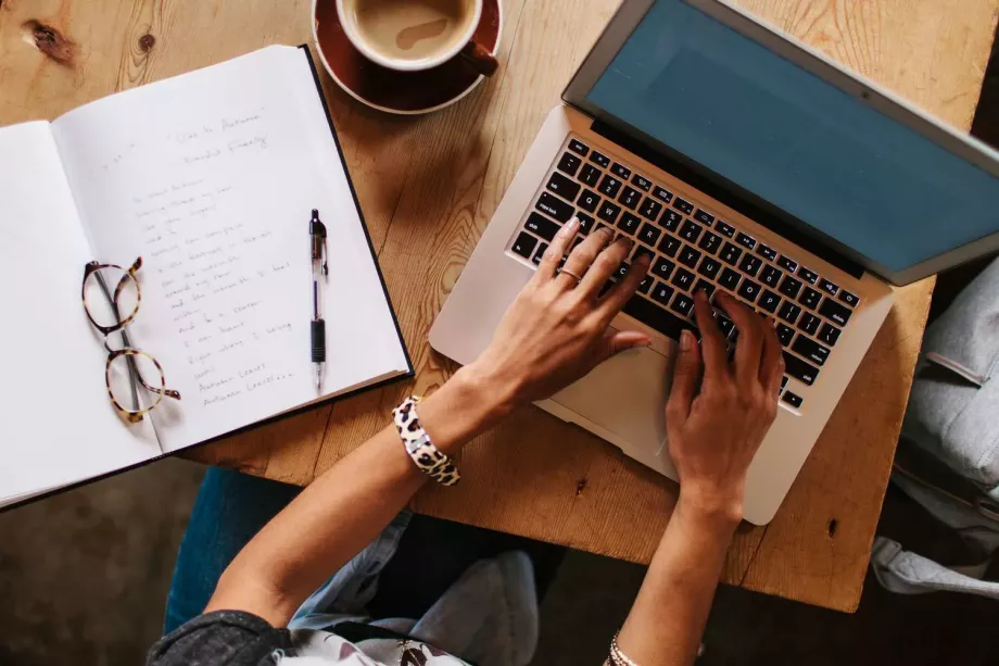 Une romancière est en train de rédiger le contenu de ses notes sur un ordinateur portable
